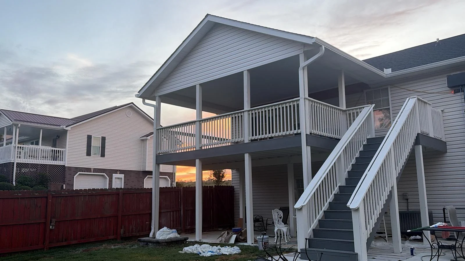 Covered custom deck with white railings and gray stairs